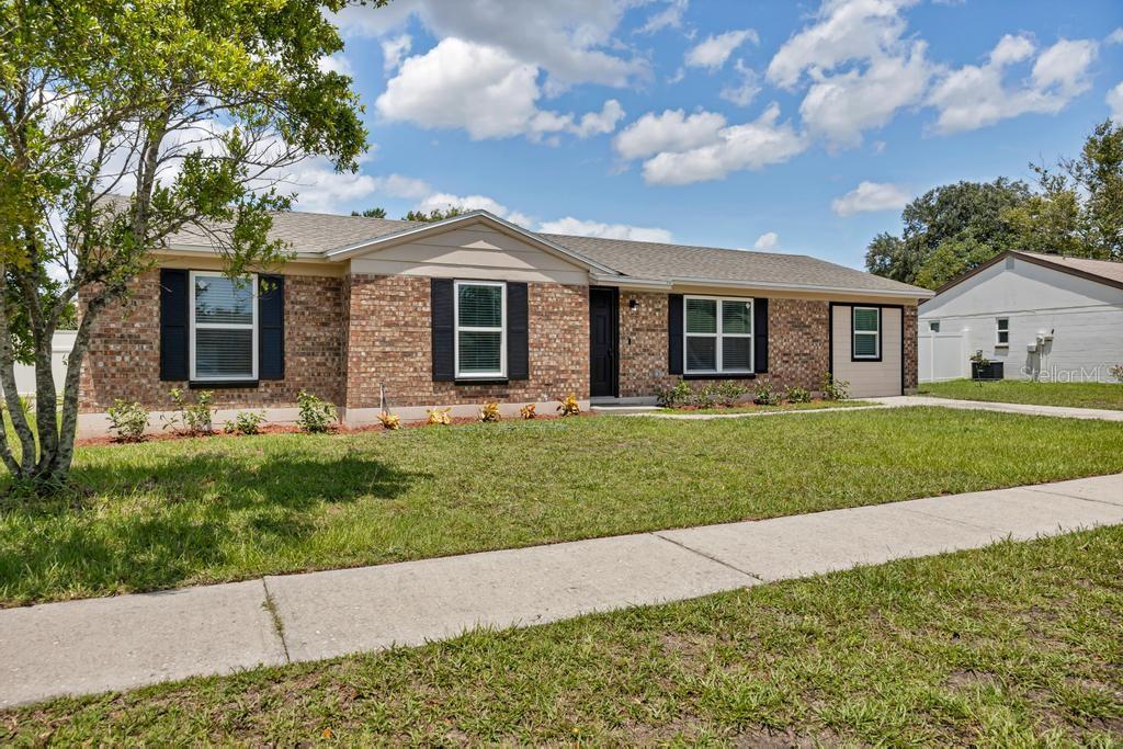 A single-story brick house with a tan gable, black shutters, and a front lawn — 8149 JUSTIN ROAD S, JACKSONVILLE, FL