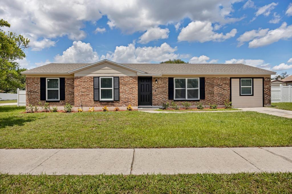 A single-story brick house with a tan roof, black shutters, and a front-facing garage — 8149 JUSTIN ROAD S, JACKSONVILLE, FL