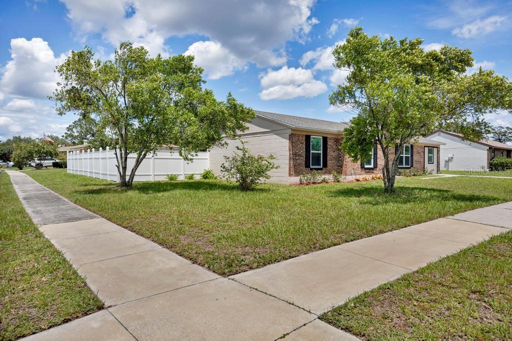 A single-story house with a brick facade and white vinyl fence sits on a corner lot — 8149 JUSTIN ROAD S, JACKSONVILLE, FL