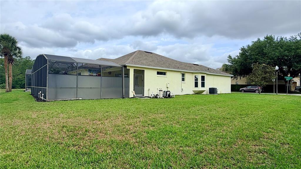The exterior of a yellow house features a screened-in patio and a large grassy yard — 660 TUPELO CIRCLE, DAVENPORT, FL