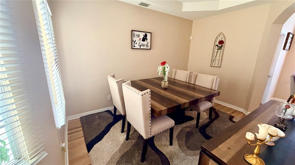 A dining room features a wooden table, four upholstered chairs, and a patterned area rug — 660 TUPELO CIRCLE, DAVENPORT, FL