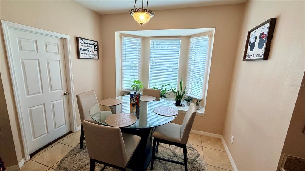 A dining area features a glass-topped table, four upholstered chairs, and a bay window — 660 TUPELO CIRCLE, DAVENPORT, FL