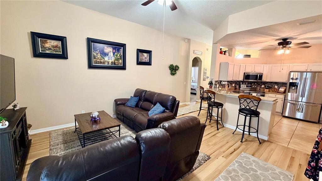 A living room with brown leather furniture opens into a kitchen with white cabinets — 660 TUPELO CIRCLE, DAVENPORT, FL