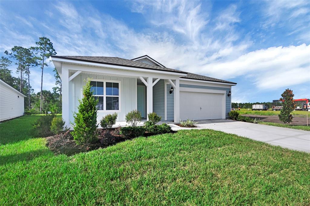 A single-story house with light blue siding, a white front porch, and a concrete driveway — 306 FISHTAIL PLACE, PALM COAST, FL
