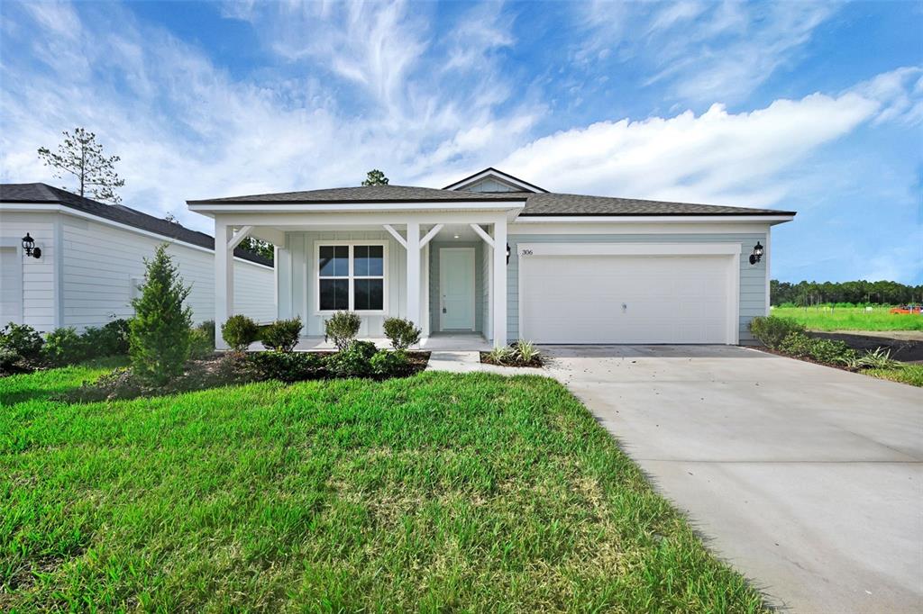 A single-story house with light blue siding, a covered porch, and a two-car garage — 306 FISHTAIL PLACE, PALM COAST, FL