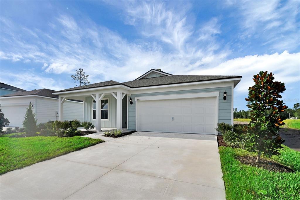 A light blue single-story house features a two-car garage and a covered front porch — 306 FISHTAIL PLACE, PALM COAST, FL