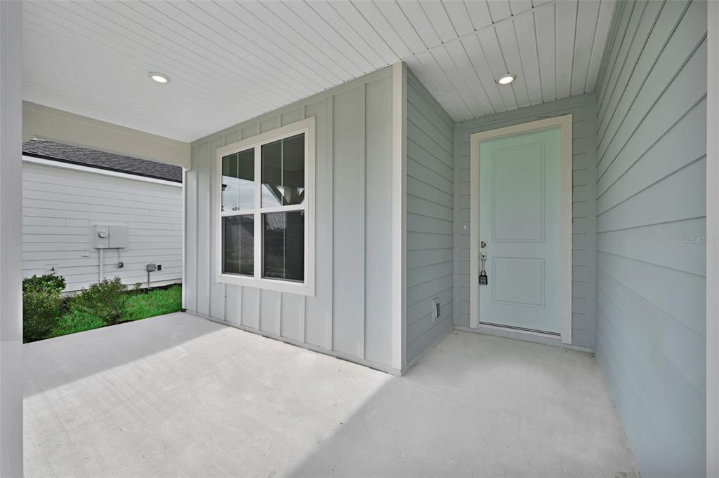A covered concrete porch features light blue siding, a light blue front door, and windows — 306 FISHTAIL PLACE, PALM COAST, FL