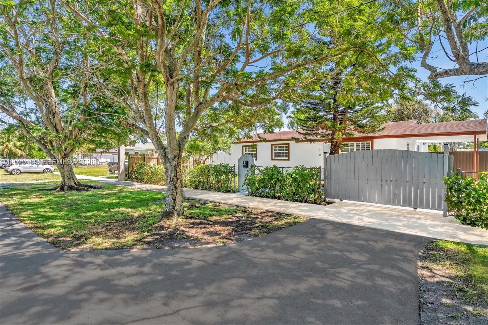 A single-story house with a white exterior, a gray gate, and large trees in front — 11790 SW 34th St, Miami FL 33175, MIAMI, FL