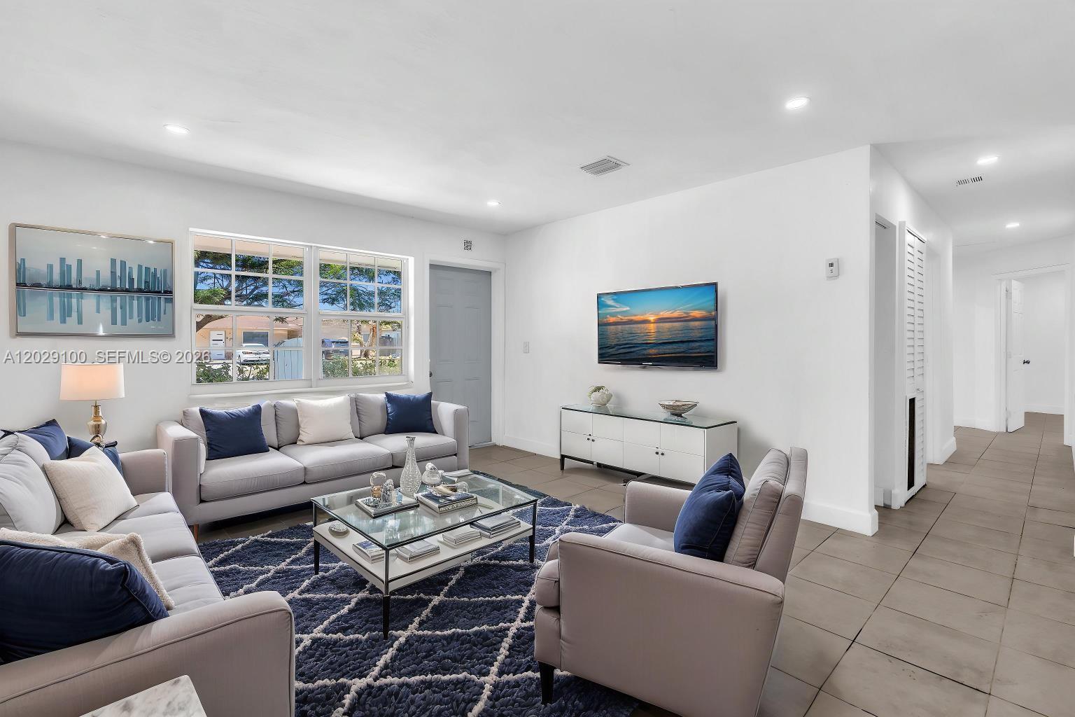 A living room features a grey sofa, matching armchair, glass coffee table, and wall-mounted television — 11790 SW 34th St, Miami FL 33175, MIAMI, FL