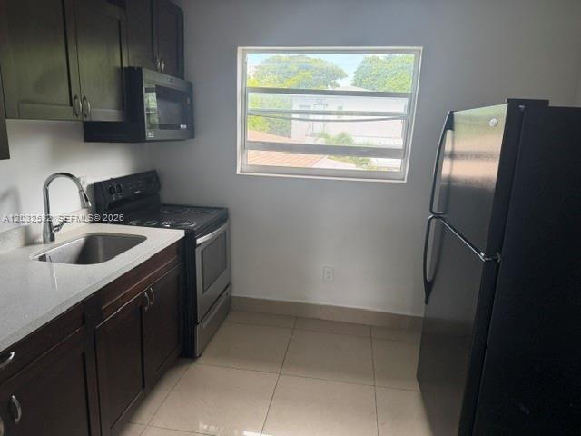 A kitchen features dark wood cabinets, stainless steel appliances, a window, and light tile flooring — 1045 SW 4th St # 5, Miami FL 33130, MIAMI, FL