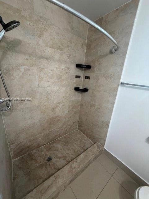A walk-in shower with tan stone tile walls, a curved rod, and built-in corner shelves — 1045 SW 4th St # 5, Miami FL 33130, MIAMI, FL