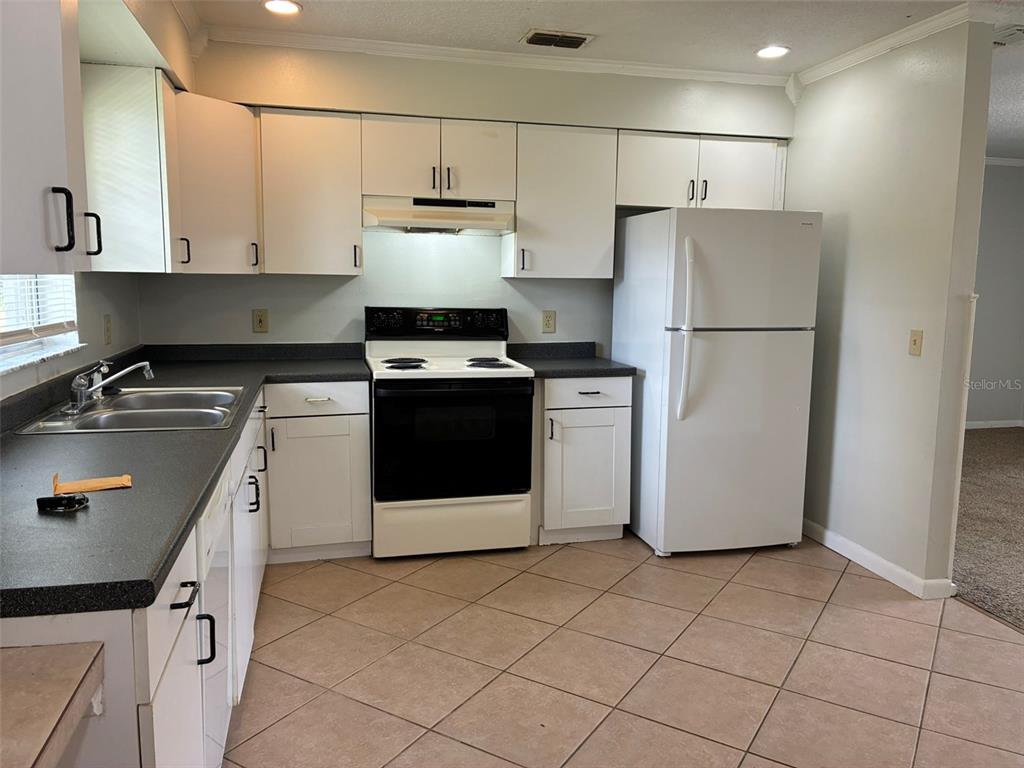 A kitchen features white cabinets, dark countertops, a white stove, and a white refrigerator — 320 QUEEN AVENUE, OVIEDO, FL