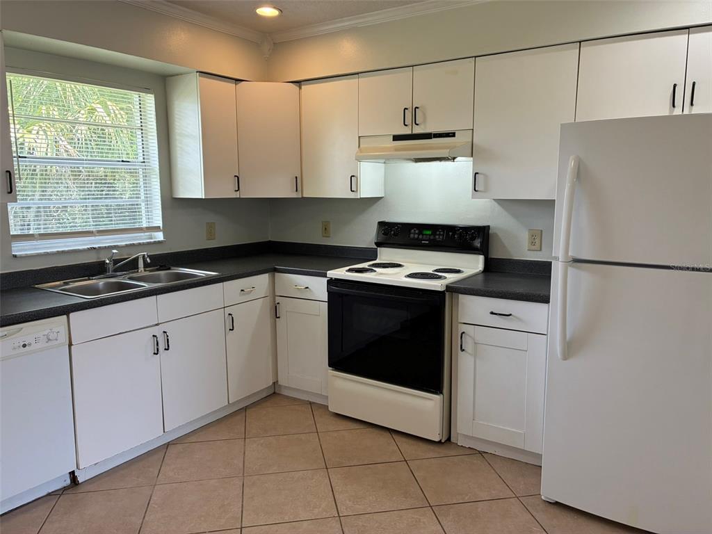 A kitchen with white cabinets, dark countertops, a white stove, and a white refrigerator — 320 QUEEN AVENUE, OVIEDO, FL