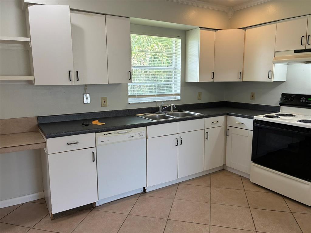 A kitchen features white cabinets, dark countertops, a double sink, and white appliances — 320 QUEEN AVENUE, OVIEDO, FL