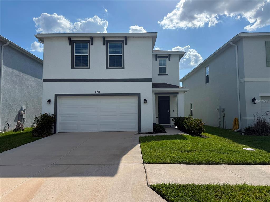 A two-story house with a white stucco exterior, a two-car garage, and a front entrance — 2763 COMMON FIG RUN, WESLEY CHAPEL, FL