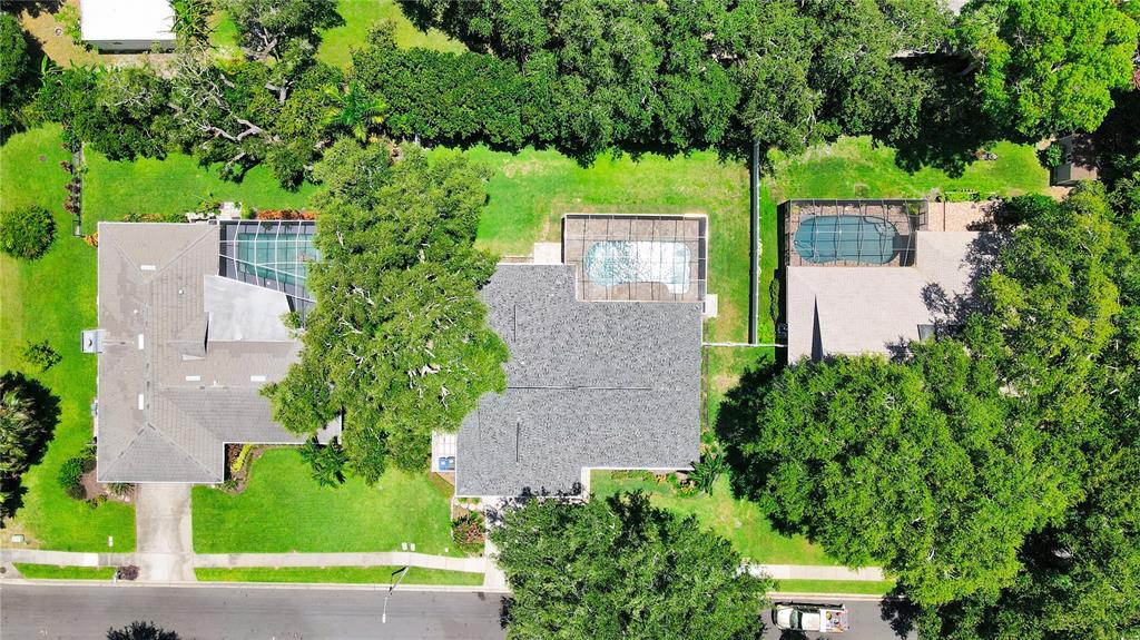 An aerial view shows three houses with screened-in pools surrounded by lush green lawns and trees — 2905 BLUFFS DRIVE, LARGO, FL