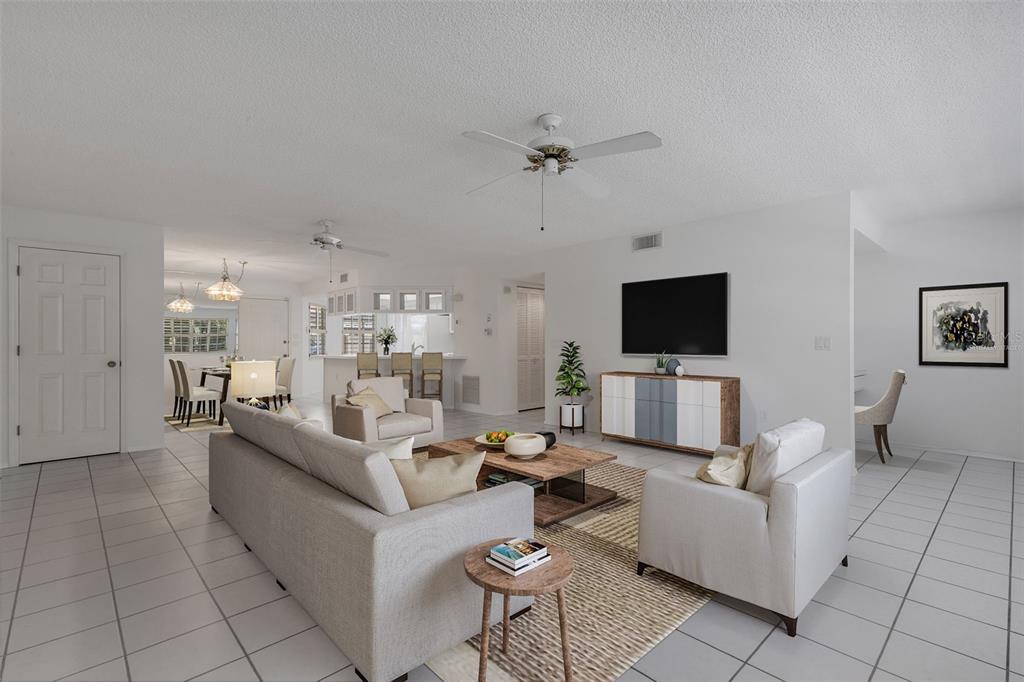 A bright living room features white tile floors, a ceiling fan, and a wall-mounted television — 528 W VENICE AVENUE UNIT # 1, VENICE, FL