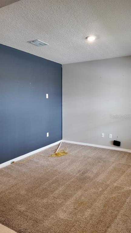 An empty room features beige carpeting, a dark blue accent wall, and light gray walls — 11237 AMBER RIDGE DRIVE, ZELLWOOD, FL