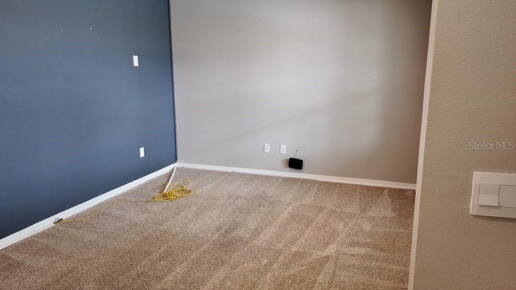 An empty room features beige carpet, a dark blue accent wall, and a light gray wall — 11237 AMBER RIDGE DRIVE, ZELLWOOD, FL