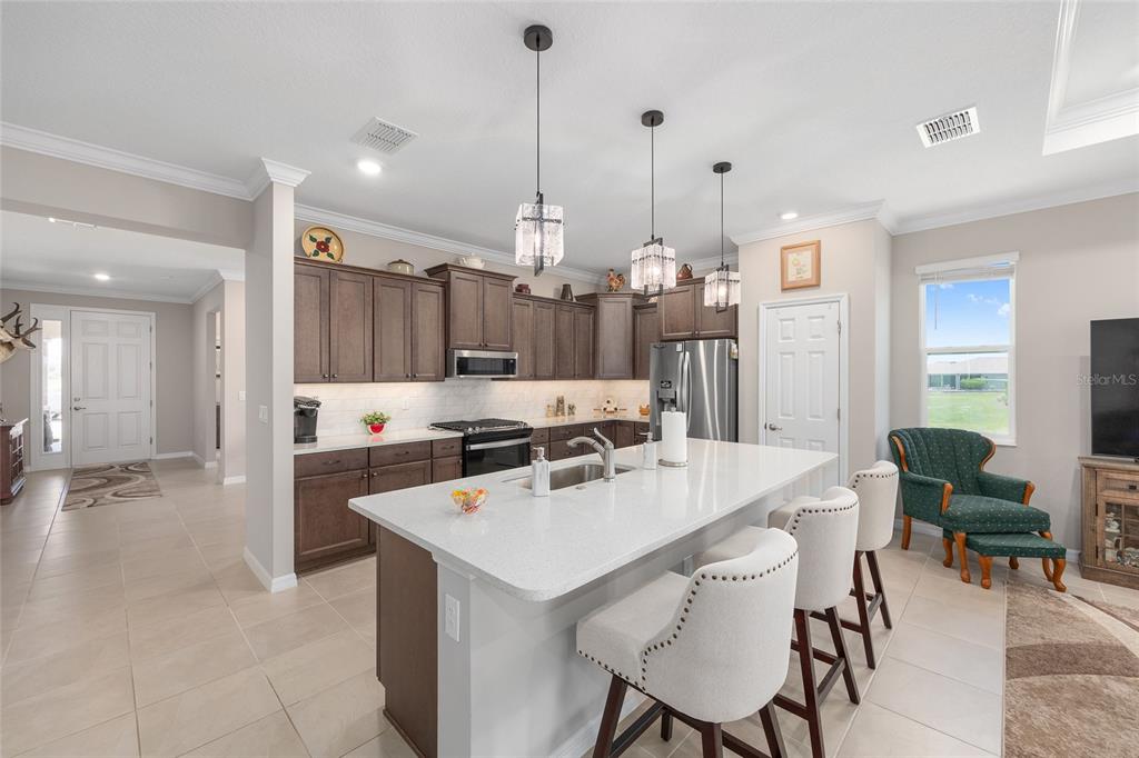 A kitchen features dark wood cabinets, a white quartz island, and three pendant lights — 7175 SW 86TH COURT, OCALA, FL