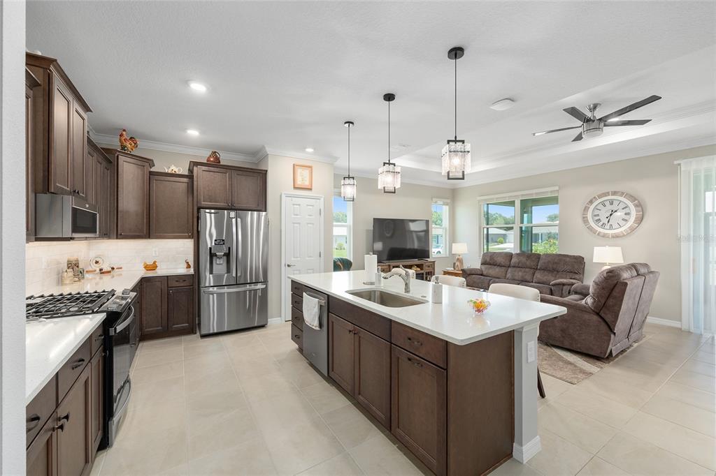 A kitchen with dark wood cabinets, stainless steel appliances, and a central island with seating — 7175 SW 86TH COURT, OCALA, FL