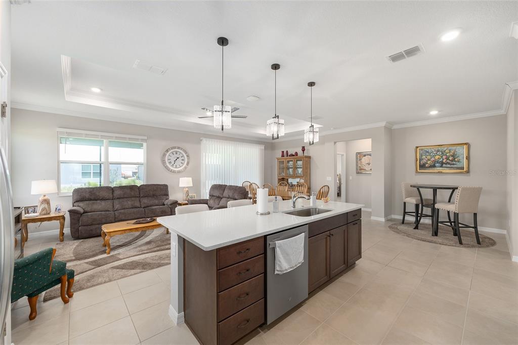 An open-concept kitchen with a central island overlooks a living area and dining space — 7175 SW 86TH COURT, OCALA, FL