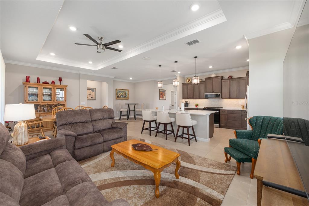 An open-concept living room and kitchen featuring brown furniture, a kitchen island, and tile flooring — 7175 SW 86TH COURT, OCALA, FL