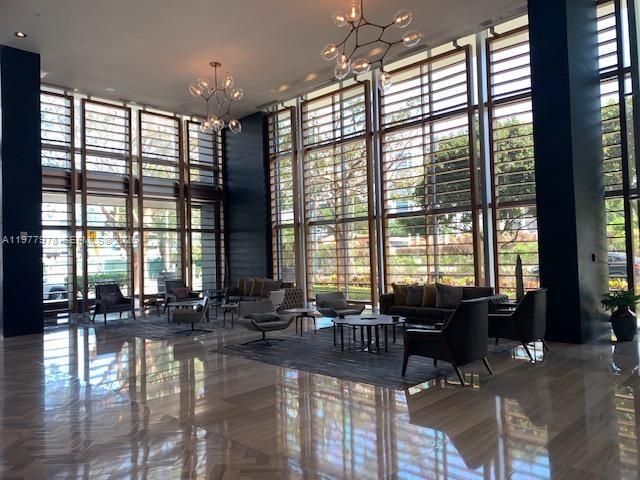 A modern lobby features floor-to-ceiling windows, polished tile floors, and contemporary seating areas — 3470 E Coast Ave # H0708, Miami FL 33137, MIAMI, FL