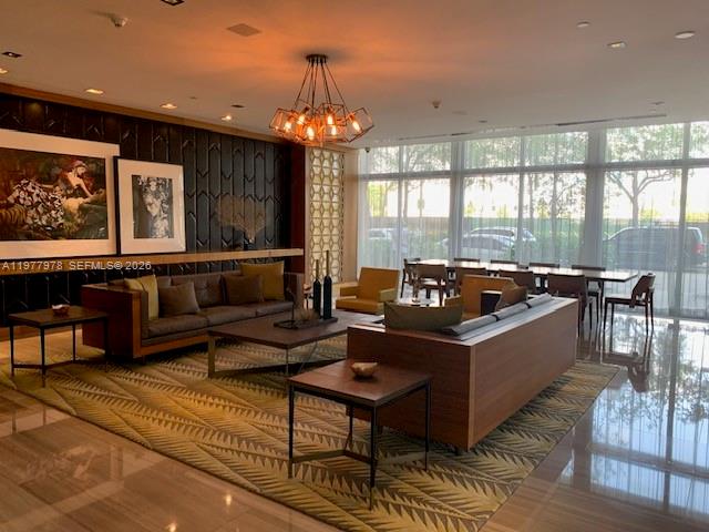 A modern lobby features a large sofa, patterned area rug, and a decorative chandelier — 3470 E Coast Ave # H0708, Miami FL 33137, MIAMI, FL