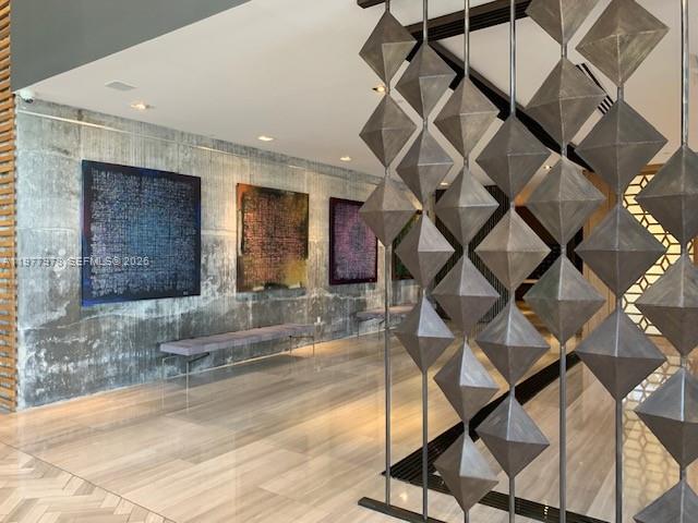 A modern lobby features concrete walls, abstract artwork, a bench, and a geometric metal screen — 3470 E Coast Ave # H0708, Miami FL 33137, MIAMI, FL