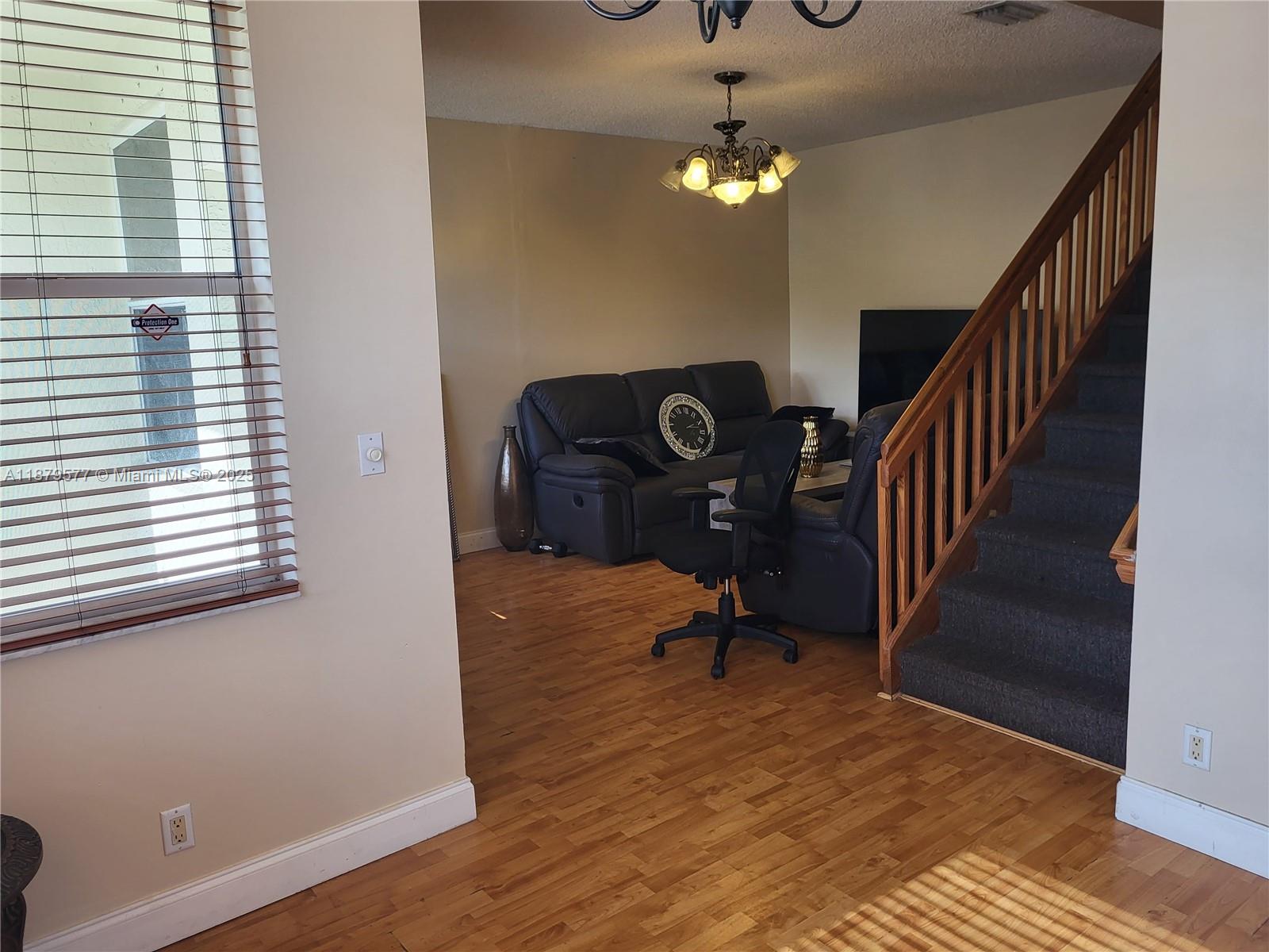 A living room features hardwood floors, a dark leather sofa, and a staircase with wooden railings — 820 NE 212th Ter # 6, Miami FL 33179, MIAMI, FL