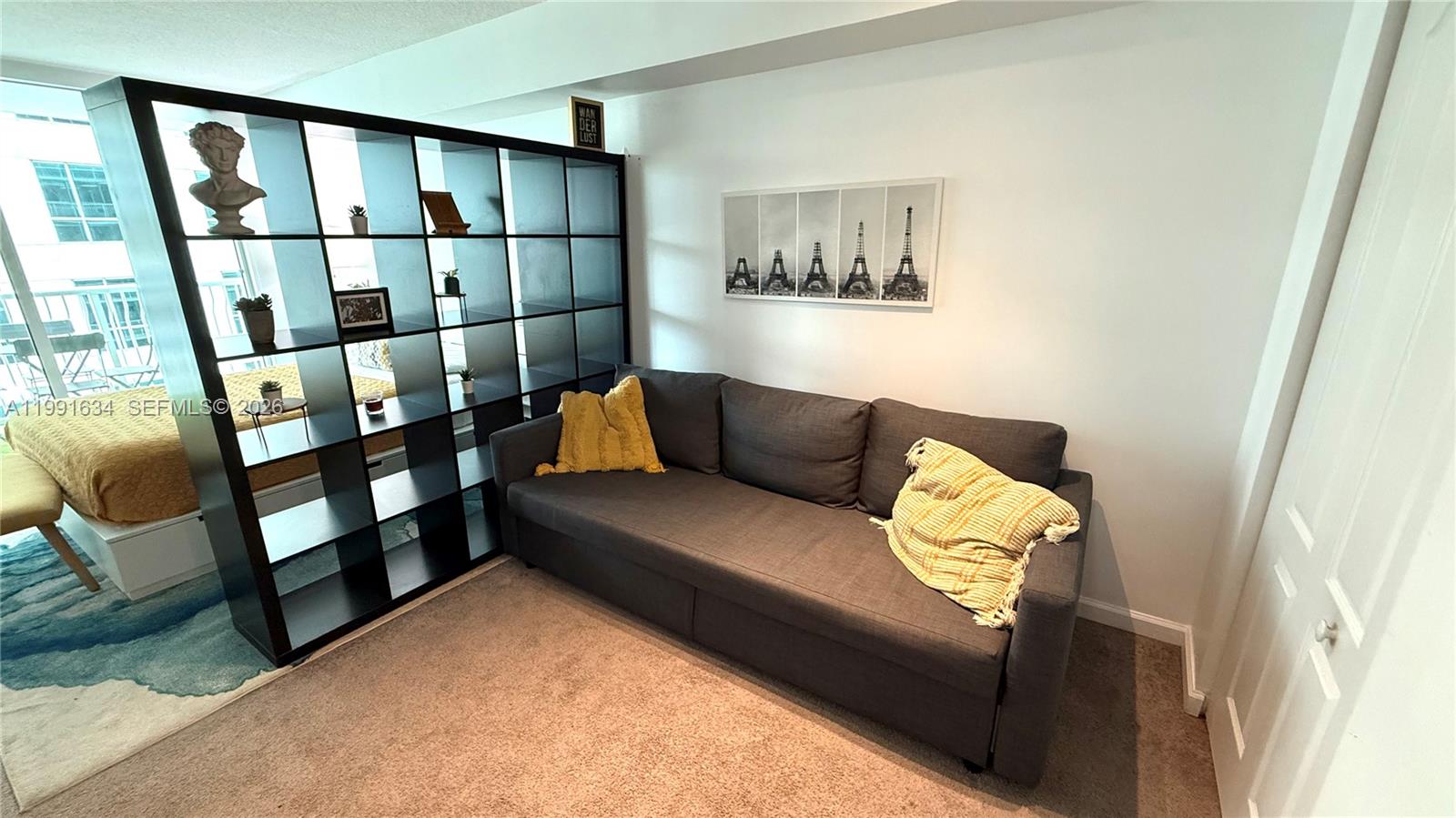 A living area features a gray sofa, a black room divider, and wall art — 1200 Brickell Bay Dr # 2216, Miami FL 33131, MIAMI, FL