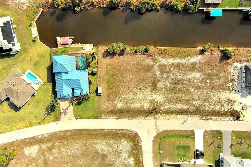 An aerial view shows a vacant residential lot next to a house with a pool — 1939 NW 34TH PLACE, CAPE CORAL, FL