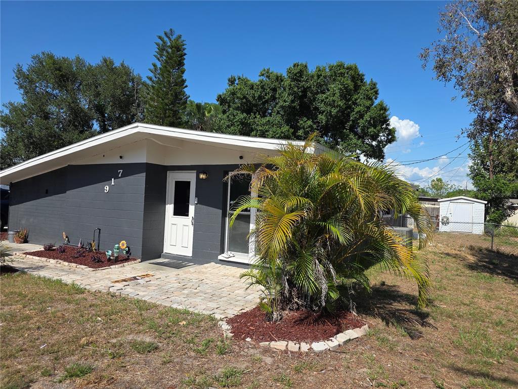 A single-story house with dark gray siding, a white door, and a stone patio — 917 27TH STREET E, BRADENTON, FL