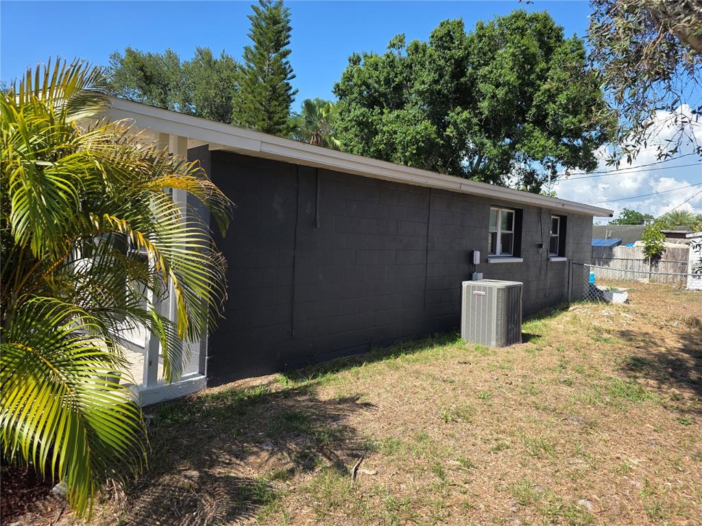 The exterior side of a dark gray concrete block house features an air conditioning unit — 917 27TH STREET E, BRADENTON, FL