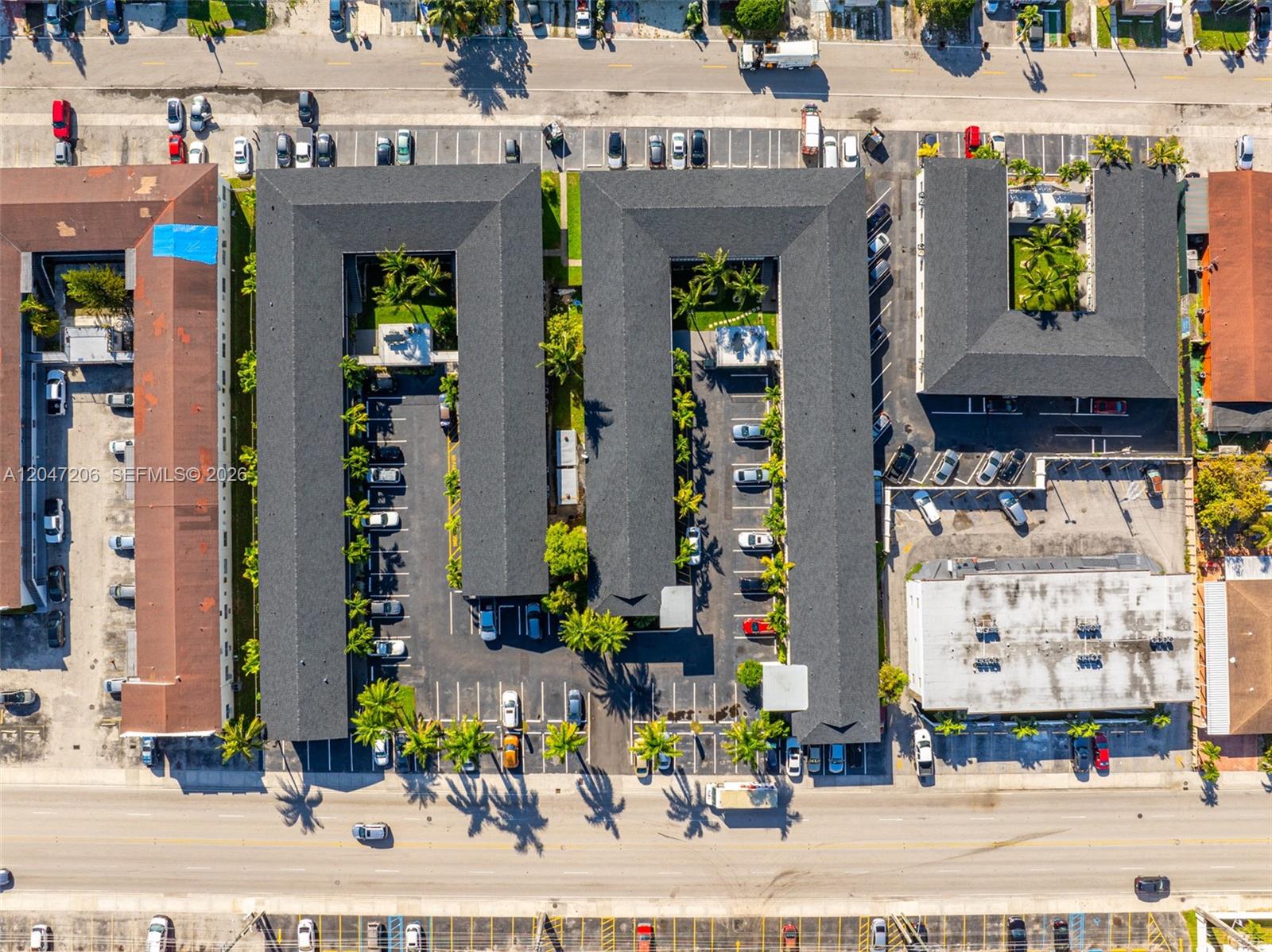 An aerial view shows multiple apartment buildings with dark roofs, parking lots, and palm trees — 1330 W 29th St # 34, Hialeah FL 33012, HIALEAH, FL