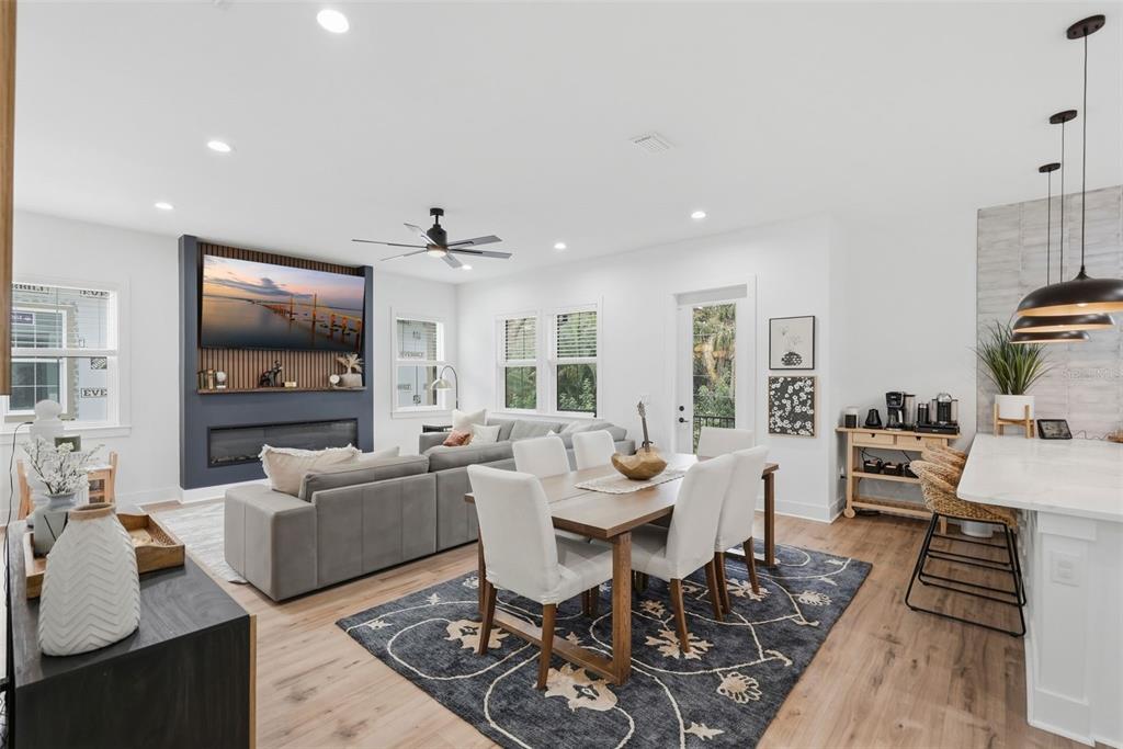 An open-concept living and dining area features a fireplace, gray sofa, and wood flooring — 1727 MARYLAND AVENUE NE, ST PETERSBURG, FL