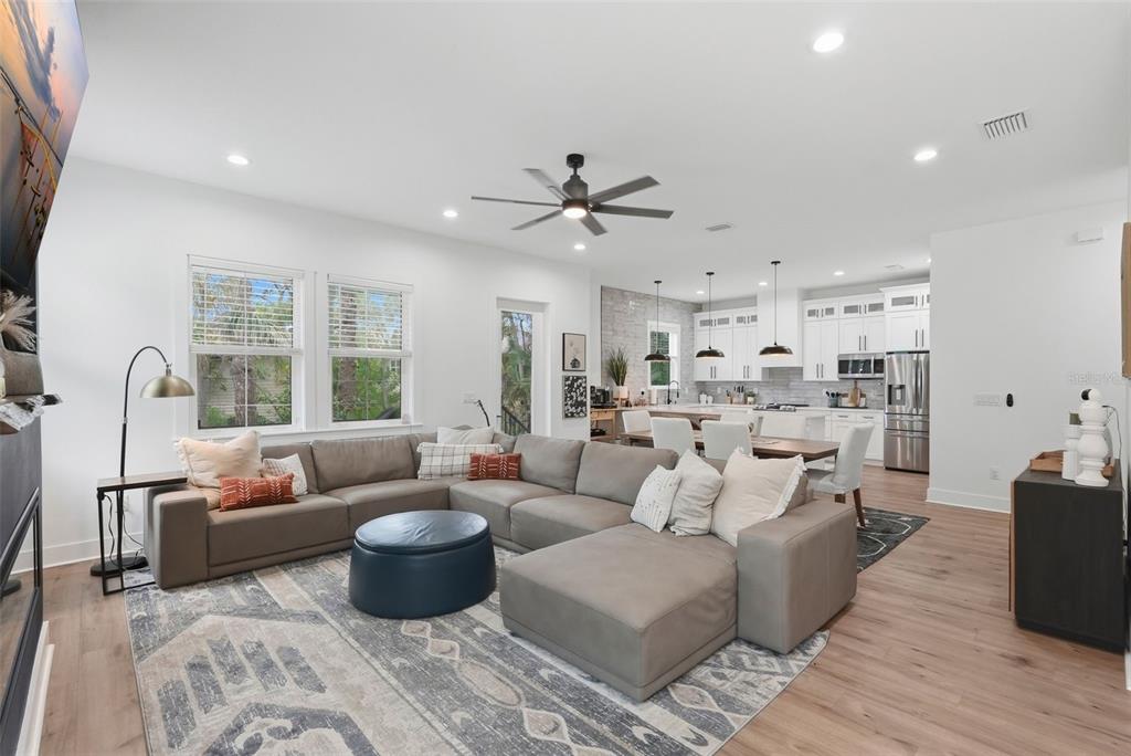 A living room with a gray sectional sofa, area rug, and an open-concept kitchen beyond — 1727 MARYLAND AVENUE NE, ST PETERSBURG, FL