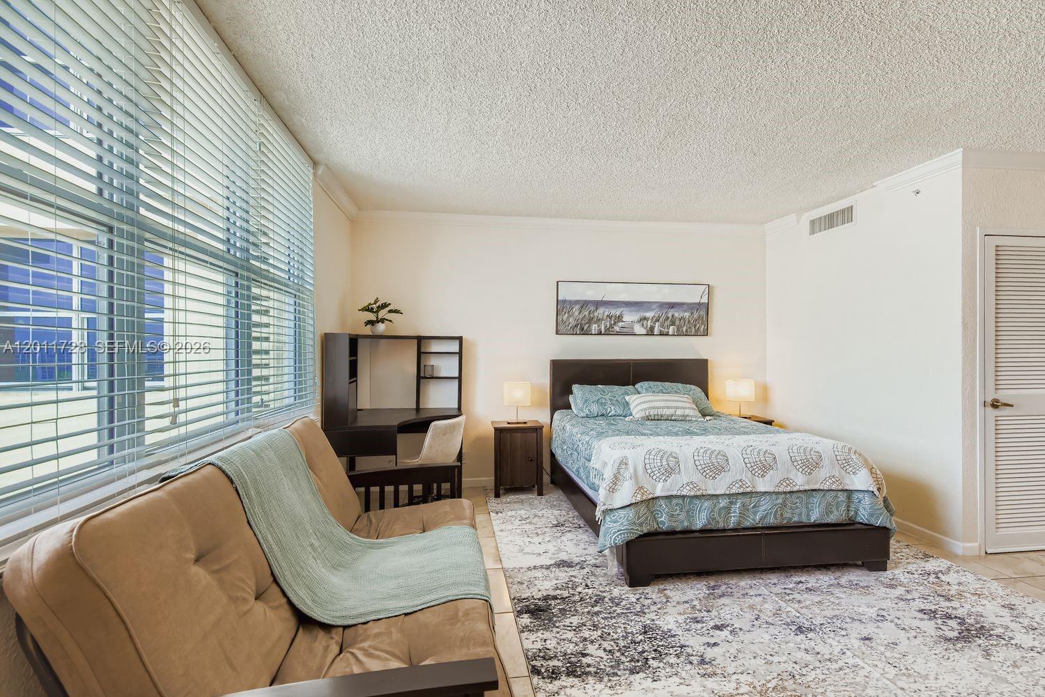 A bedroom features a bed, a desk, a sofa, and large windows with blinds — 2501 S Ocean Dr # 1032, Hollywood FL 33019, HOLLYWOOD, FL