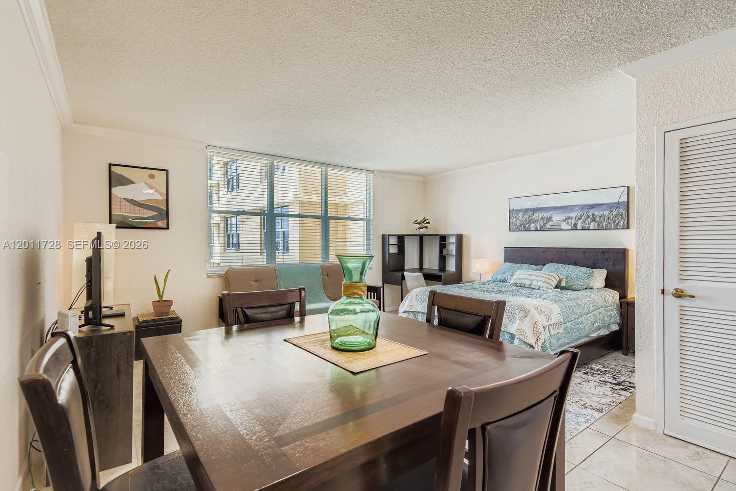 A studio apartment features a dining table, a bed, and a desk near a window — 2501 S Ocean Dr # 1032, Hollywood FL 33019, HOLLYWOOD, FL