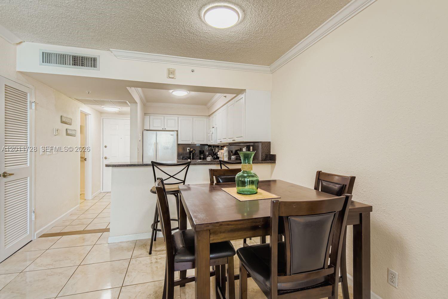 A dining area with a wooden table and chairs sits adjacent to an open kitchen — 2501 S Ocean Dr # 1032, Hollywood FL 33019, HOLLYWOOD, FL