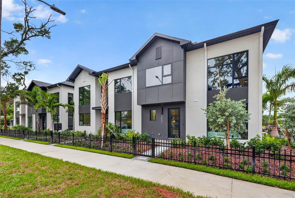 A modern multi-unit townhouse exterior with gray and white siding, large windows, and black fencing — 3601 1ST AVENUE N, ST PETERSBURG, FL