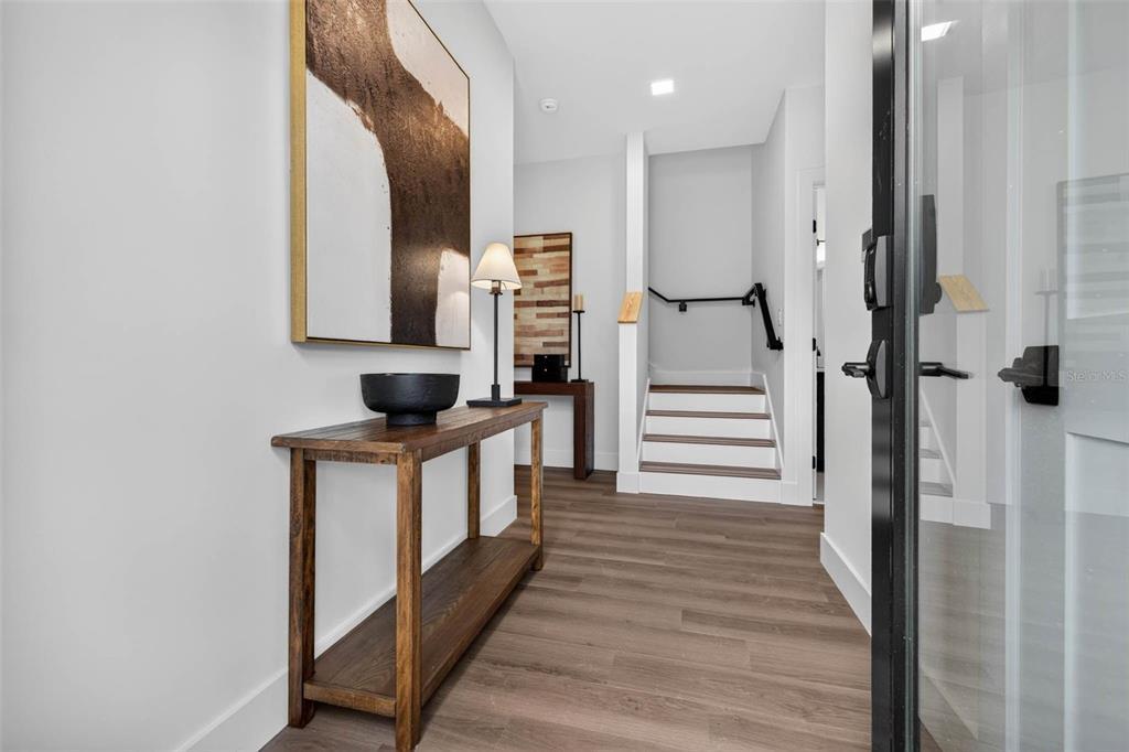 An entryway features wood-look flooring, a console table, wall art, and stairs leading upward — 3601 1ST AVENUE N, ST PETERSBURG, FL