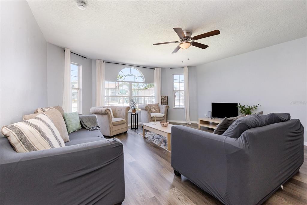 A living room features gray sofas, a coffee table, and a ceiling fan — 8711 ROCKINGHAM TERRACE UNIT A, KISSIMMEE, FL