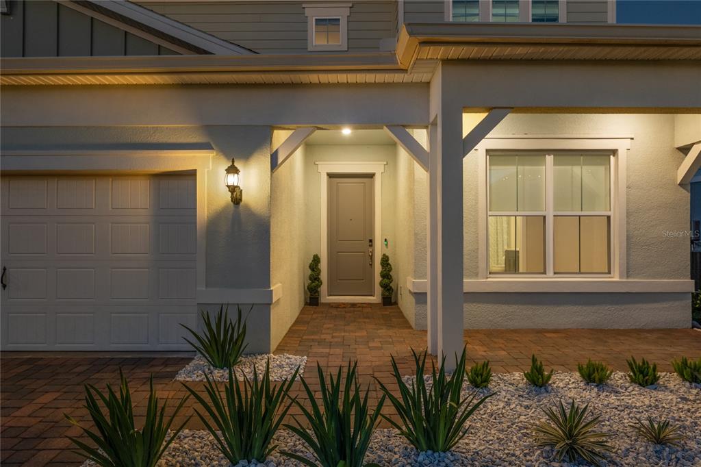 The exterior of a house features a paved walkway, a gray front door, and landscaping — 13363 PANAMA BEACH COURT, ORLANDO, FL
