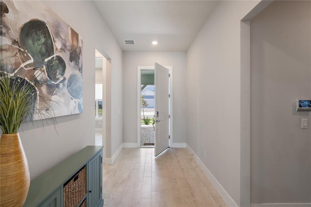 A bright entryway features light wood-look tile flooring, a blue console table, and an open door — 13363 PANAMA BEACH COURT, ORLANDO, FL