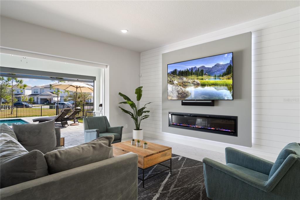 A living room features a wall-mounted television above a linear fireplace and a sliding door — 13363 PANAMA BEACH COURT, ORLANDO, FL