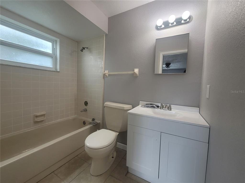 A bathroom features a white vanity, a toilet, and a tiled bathtub shower combination — 9900 SWEEPSTAKES LANE UNIT 3, ORLANDO, FL