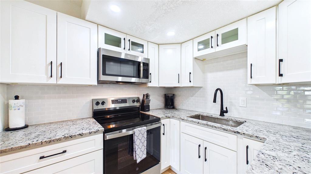 A kitchen features white cabinets, granite countertops, stainless steel appliances, and a subway tile backsplash — 3789 46TH AVENUE S UNIT 204, ST PETERSBURG, FL