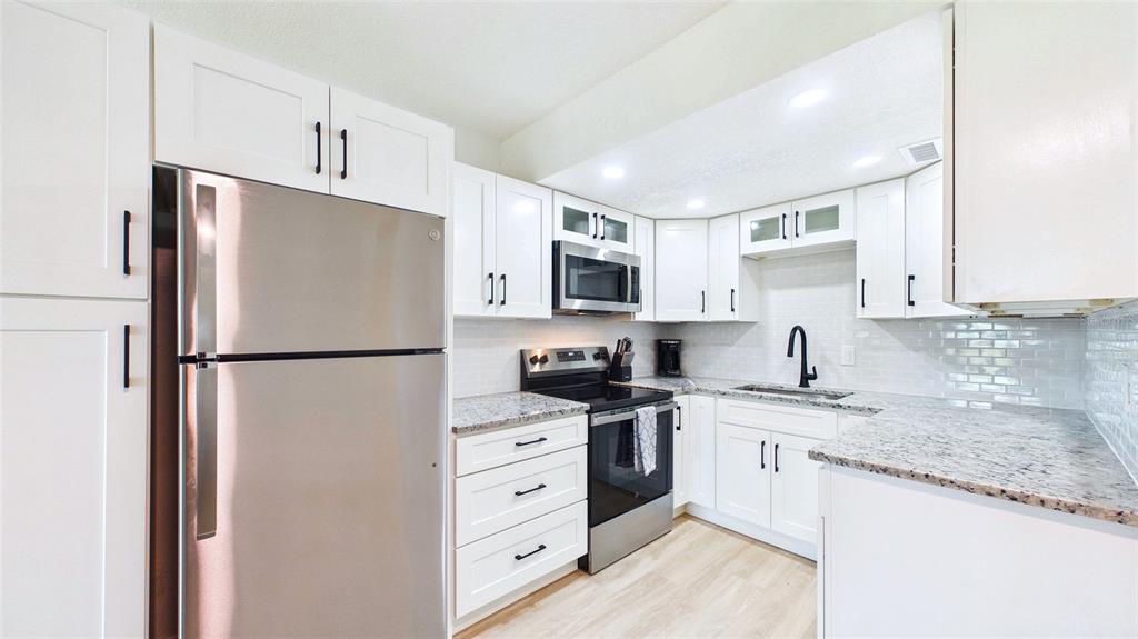 A kitchen features white cabinets, granite countertops, stainless steel appliances, and a subway tile backsplash — 3789 46TH AVENUE S UNIT 204, ST PETERSBURG, FL